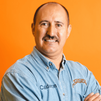 Santos smiling in front of orange background in Food Forward shirt reading Calderon