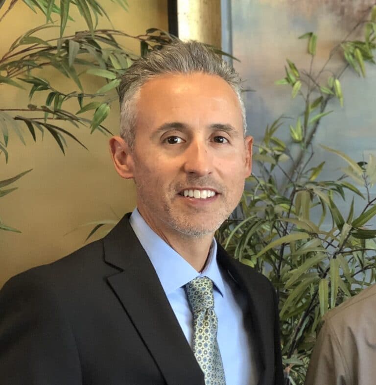 Rod Cordova smiling in suit in front of plants