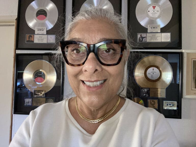 Suki Sir Smiling in front of framed records