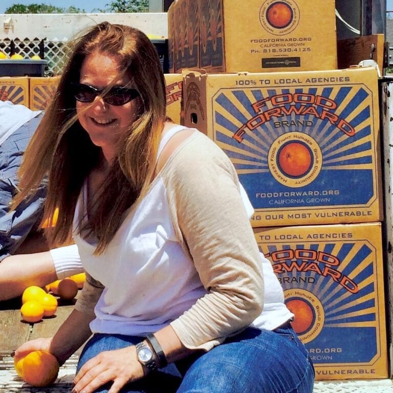 Nancy Volpert in sunglasses in front of Food Forward boxes