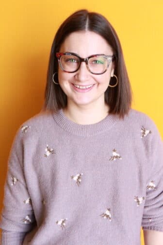 Woman with glasses in front of orange background