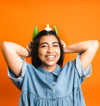 Aubrey holding green peppers as if they're ears while balancing mushroom on head