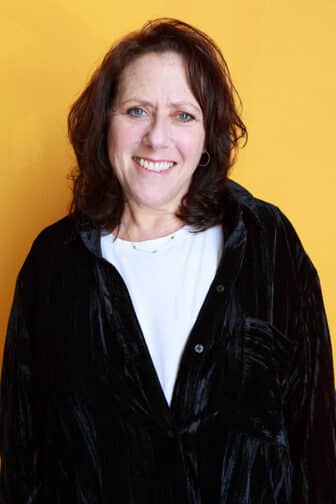 Jodi smiling in front of an orange background