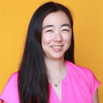 Janet smiling in front of orange background