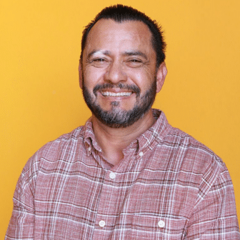 Jose smiling in front of orange background