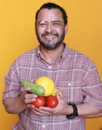 Jose smiling with a handful of fruits and vegetables