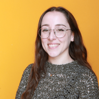 Kelsey smiling in front of orange background