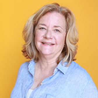 Ellen smiling in front of orange background