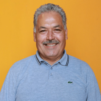 Victor smiling in front of orange background